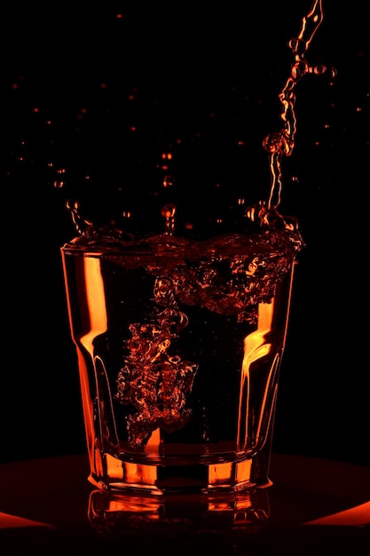 Versare l'acqua in un bicchiere. Bicchiere da whisky con acqua