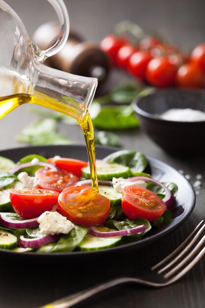 Versare l'olio d'oliva sull'insalata con pomodoro e cetriolo