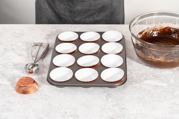 Versare la pastella per cupcake nelle fodere per cupcake per cuocere i cupcakes al cioccolato e fragole