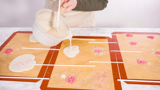 Versare lo zucchero caramellato sui tappetini in silicone per fare i lecca lecca fatti in casa.