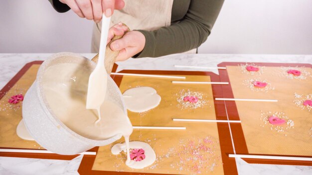 Versare lo zucchero caramellato sui tappetini in silicone per fare i lecca lecca fatti in casa.