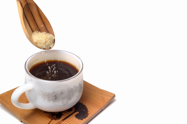 Versare lo zucchero sulla tazza di caffè su sfondo bianco