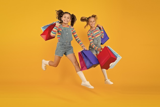 Verso l'acquisto Moda moderna Moda per bambini Bambini carini si affrettano per la stagione dei saldi Sconti e saldi Le bambine portano le borse della spesa Abiti abbinati Trendy e stravaganti Negozio di moda