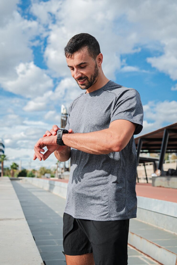 Vertical active young energetic sports man checking his progress on smart watch gear during outdoor