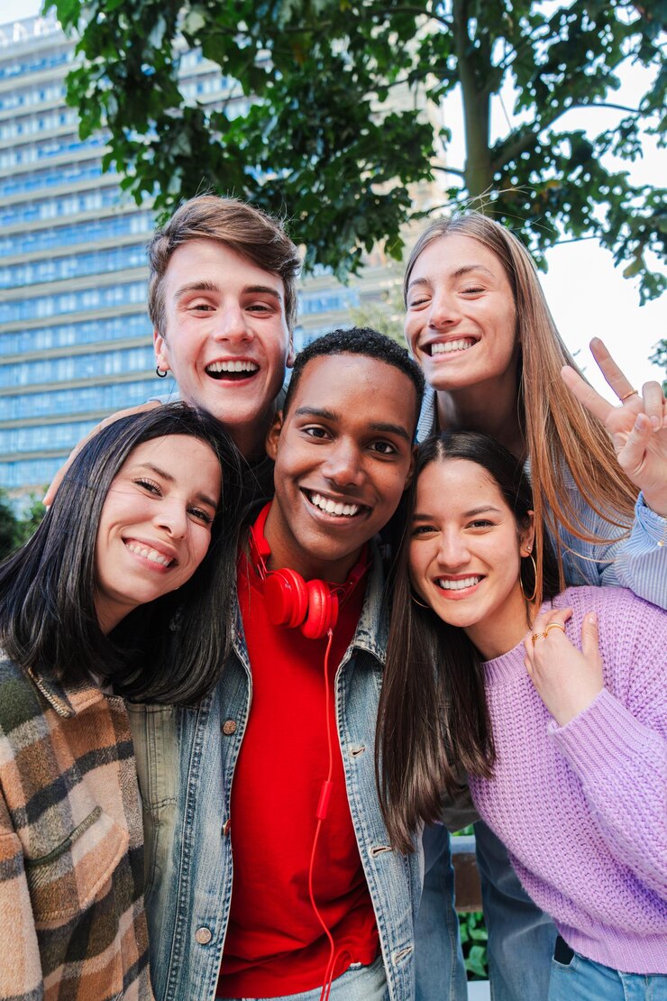 Vertical group of teenage friends embracing together and looking at camera on a party excited young