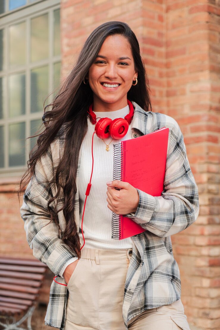 Vertical individual portrait of a pretty hispanic female student smiling and looking at camera at