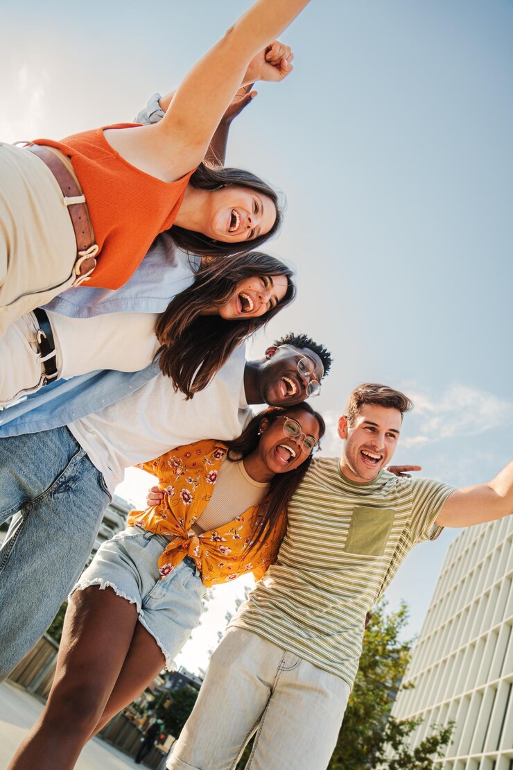 Vertical portrait of a group of smiling multiracial teenagers having fun outdoors cherful young