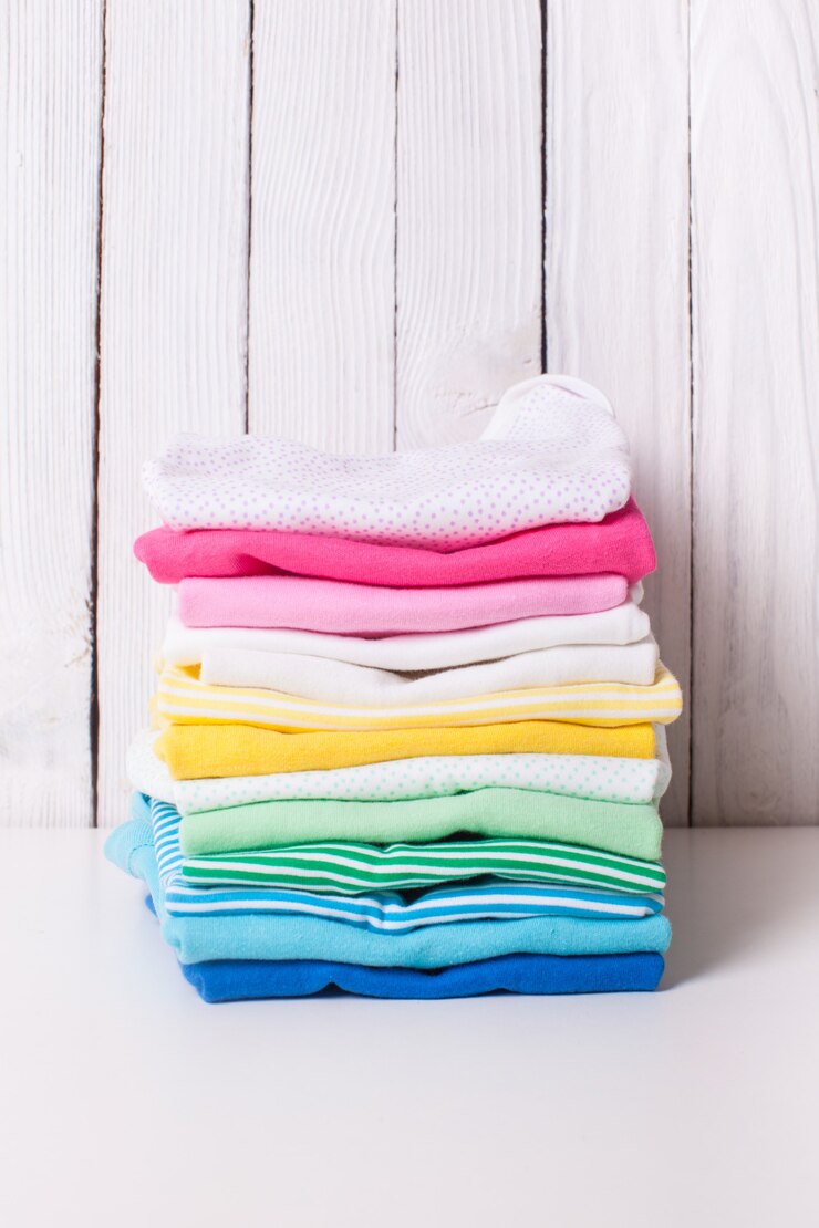 Vestiti colorati per bambini di pile piegate su sfondo bianco