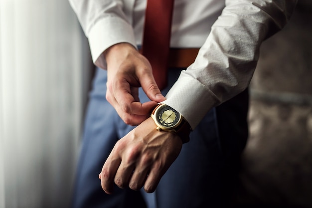 Vestiti dell'orologio dell'uomo d'affari, uomo d'affari che controlla tempo sul suo orologio. mano da uomo con orologio, orologio da uomo, spese dello sposo, preparazione del matrimonio, preparazione al lavoro