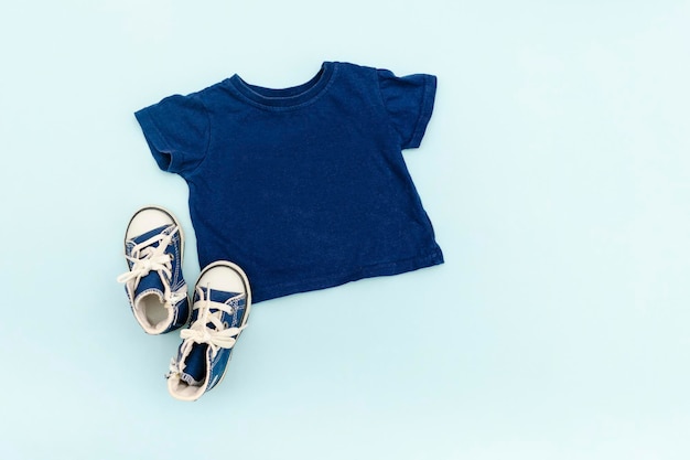 Vestiti e accessori estivi per bambini blu con maglietteSneakers Outfit per bambini alla moda modernaSet di abbigliamento per bambini per la primavera o l'estate Flat lay top viewoverheadmockup