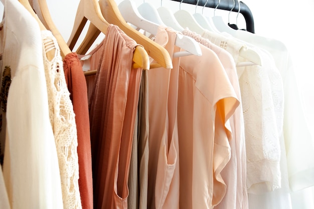 vestiti eleganti da donna appesi su uno scaffale colori naturali, concetto di tendenza, camera bianca colori pastello