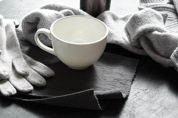 Vestiti lavorati a maglia e tazze da caffè sulla superficie nera