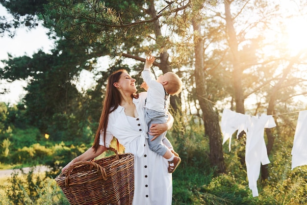 Vestiti puliti appesi alla corda per asciugare Giovane madre con il figlio piccolo è all'aperto nella foresta Bel sole