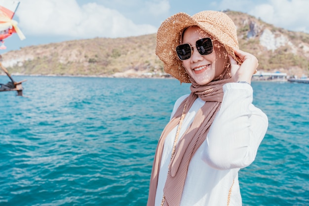 Vestito bianco dalla giovane donna musulmana sicura sulla spiaggia.