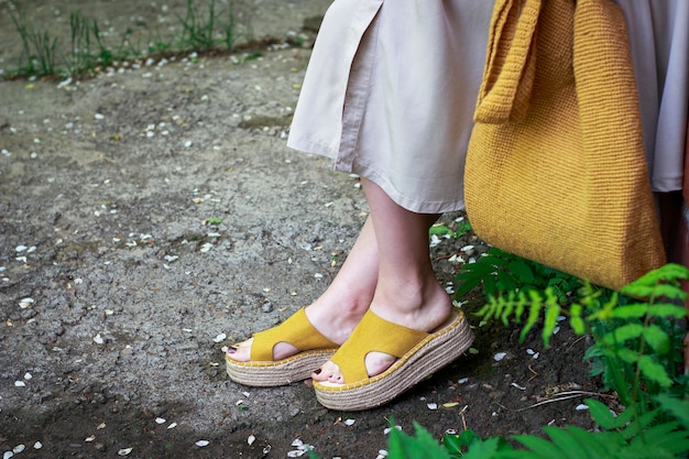 Vestito di moda estiva. Ragazza in abito, scarpe gialle e borsa a maglia alla moda, vista laterale