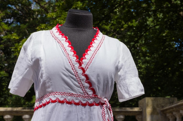 Vestizione bianca su manichino Abito bianco in tessuto naturale con elementi rossi Sartoria su misura Abito estivo da donna in cotone con cintura