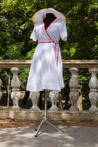 Vestizione bianca su manichino Abito bianco in tessuto naturale con elementi rossi Sartoria su misura Abito estivo da donna in cotone con cintura