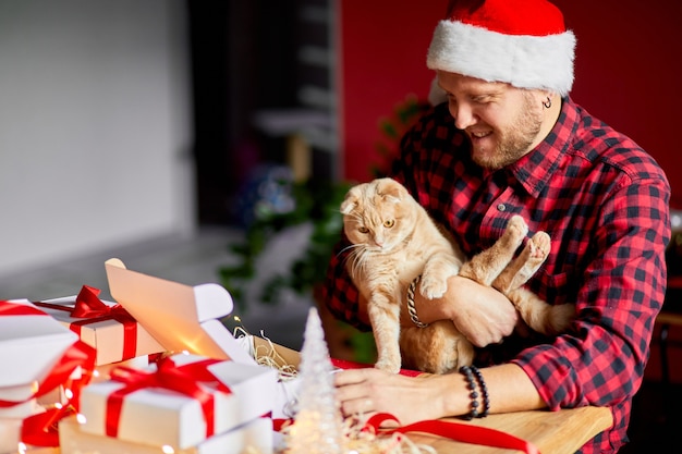 Veterinario con cappello da Babbo Natale e gatto in mano che fanno un biglietto di auguri per Capodanno e Natale