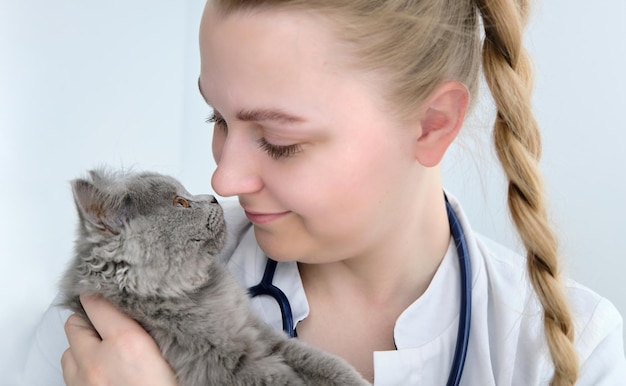 Veterinario femminile che tiene gatto carino su sfondo bianco