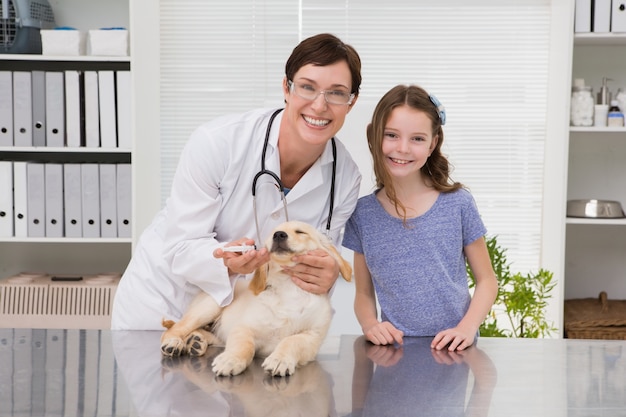 Veterinario sorridente che esamina un cane con il suo proprietario