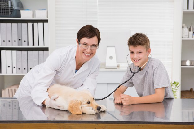 Veterinario sorridente che esamina un cane con il suo proprietario