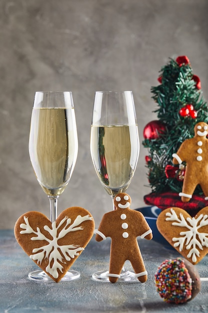 Vetri con champagne con un albero di Natale e biscotti di pan di zenzero