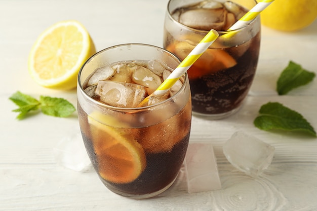 Vetri con cola fredda e gli agrumi sul fondo del cemento bianco