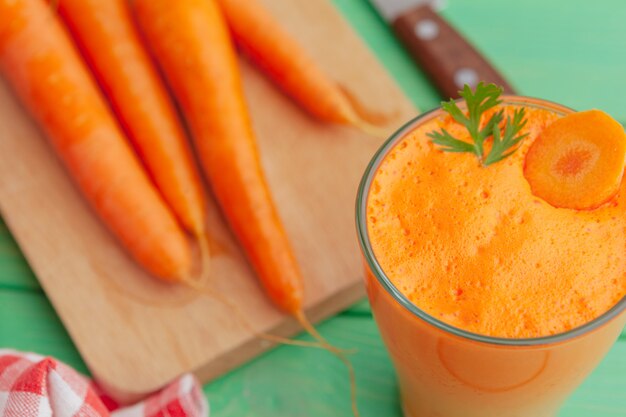 Vetri del succo di carota con le verdure sulla fine della tavola su