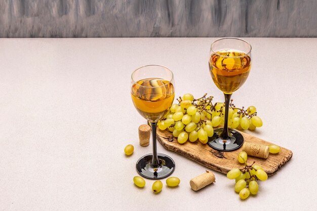 Vetri di vino, uva fresca e sugheri sul tagliere di legno