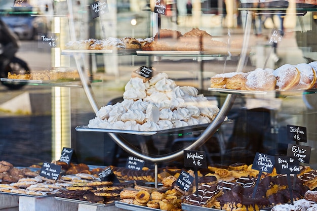 Vetrina di pasticceria accogliente con varietà di pasticcini, biscotti e torte. Iscrizione in portoghese eclair, torta, cioccolato