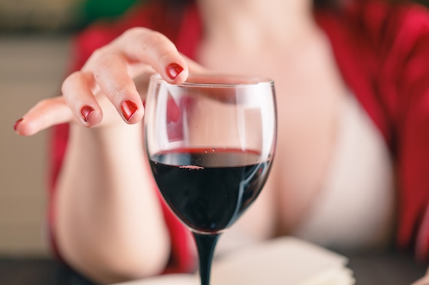 Vetro commovente della donna di vino rosso e per mezzo del suo computer portatile