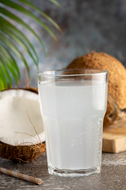 Vetro con acqua di cocco fresca e noci di cocco sul tavolo