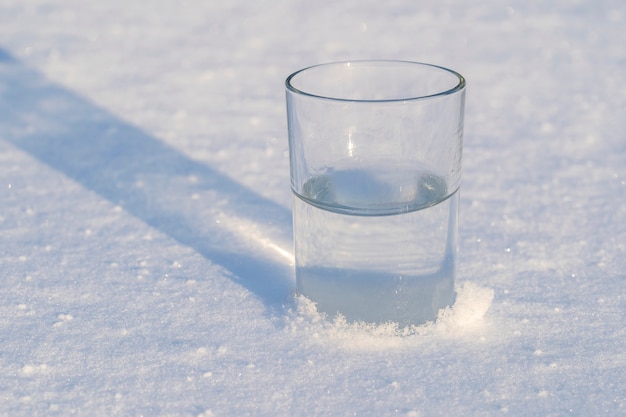 Vetro con acqua su una neve bianca in inverno, primo piano