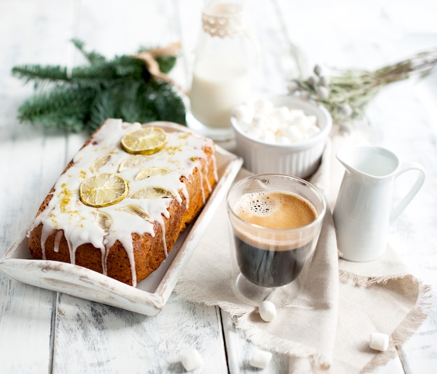 Vetro con caffè e piccoli marshmallow, torta al limone e ramo di un albero di Natale