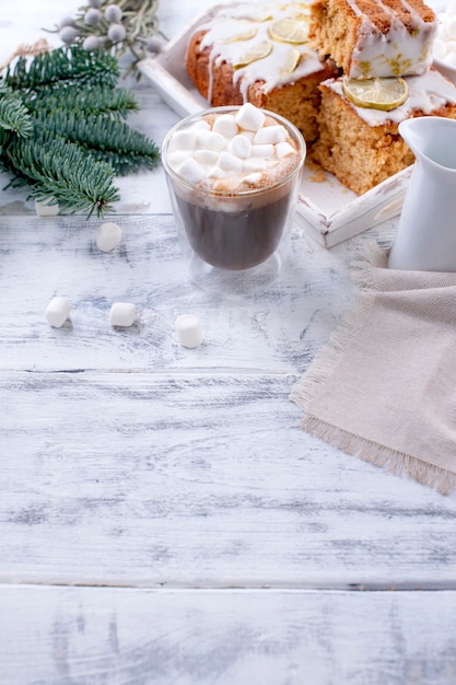 Vetro con caffè e piccoli marshmallow, torta al limone e ramo di un albero di Natale