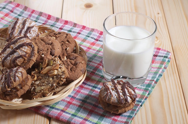 Vetro con latte e biscotti diversi su un tavolo di legno