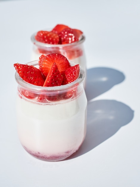 Vetro con yogurt naturale e fragole fresche, isolato su bianco