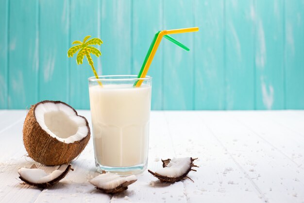 Vetro di latte di cocco sulla tavola di legno bianca