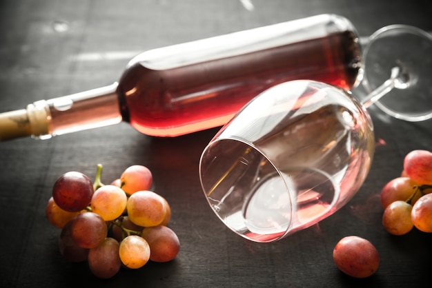 Vetro e bottiglia di vino rosato con uva