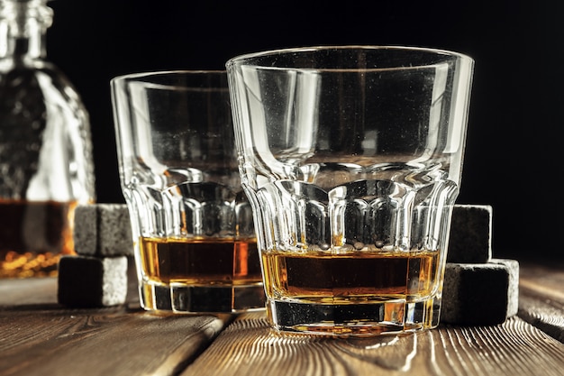 Vetro e bottiglia di whisky sulla vecchia tavola di legno