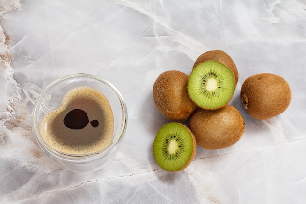 Vetro tazza di caffè e kiwi sul tavolo della cucina. Vista dall'alto.