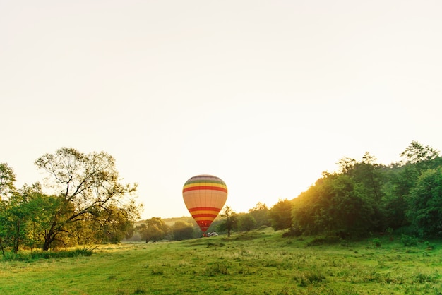 Viaggi e sport. Multi mongolfiera a strisce colorata che vola sopra la valle in cielo all'alba.