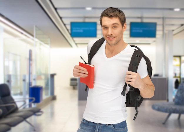 viaggi, istruzione, turismo e persone - studente sorridente con zaino e libro in aeroporto