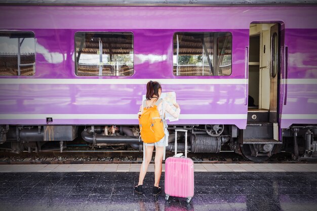 Viaggiare in treno Ragazza asiatica con borsa arancione e rosa durante le vacanze.