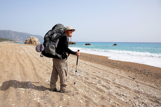 Viaggiatore barbuto con uno zaino sulla spiaggia