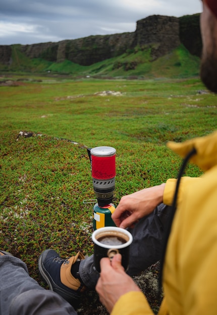 Viaggiatore che fa il caffè su un bruciatore a gas turistico rosso nella tundra settentrionale russa. Penisola di Kola