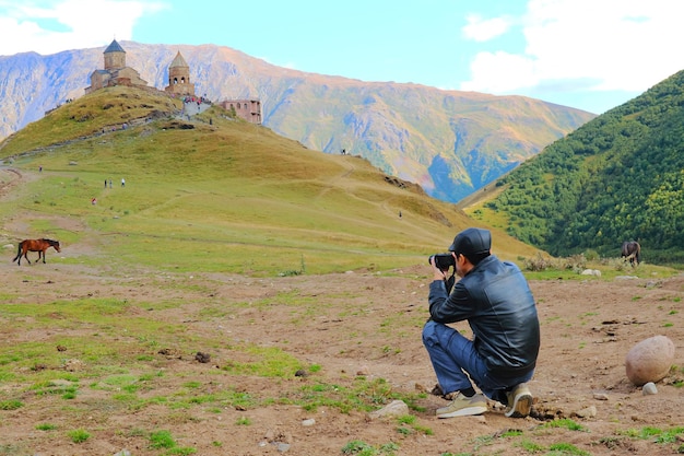 Viaggiatore che fotografa Gergeti Trinity Church nella città di Stepantsminda Kazbegi Georgia