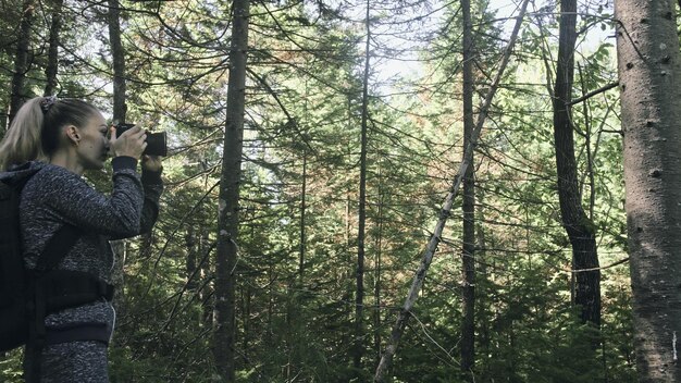 Viaggiatore che fotografa la vista panoramica nella foresta Una donna caucasica che scatta un bel look magico Ragazza scatta video fotografici su una fotocamera mirrorless dslr