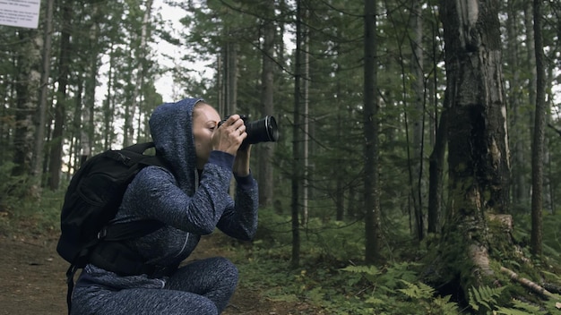 Viaggiatore che fotografa la vista panoramica nella foresta Una donna caucasica che scatta un bel look magico Ragazza scatta video fotografici su una fotocamera mirrorless dslr