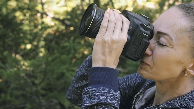 Viaggiatore che fotografa la vista panoramica nella foresta Una donna caucasica che spara uno sguardo ravvicinato La ragazza scatta un video fotografico sulla fotocamera mirrorless dslr